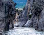 Rocas grises y aguas, con puente del diablo al fondo